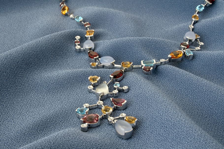assorted-color gemstone encrusted necklace on grey textile, jewelry