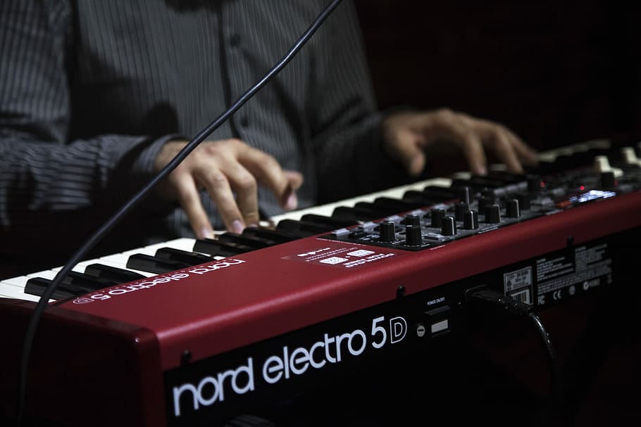 person playing red and black Nord Electro 5d keyboard, person playing maroon Nord Electro 5 electronic keyboard