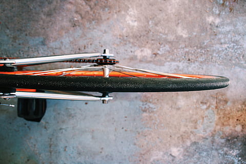 bicycle wheel on gray surface, bike wheel photograph, black and orange HD wallpaper