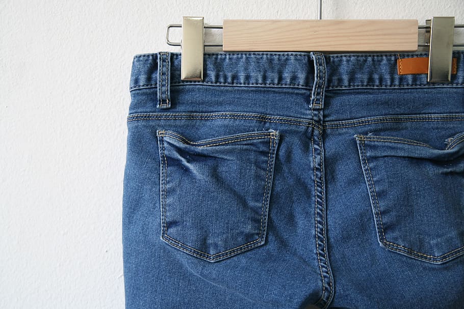 blue denim bottoms hanged on wooden hanger in close-up photography
