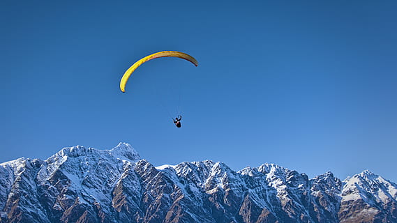 man on parachute near the mountain, person wearing yellow paragliding with background of mountain HD wallpaper