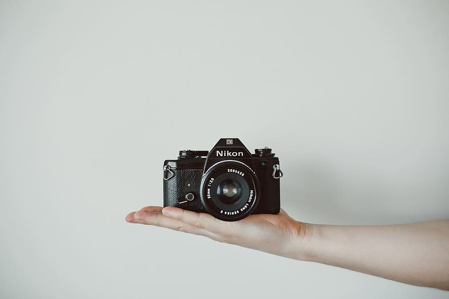 person holding Nikon DSLR camera, black Nikon camera on person hand HD wallpaper