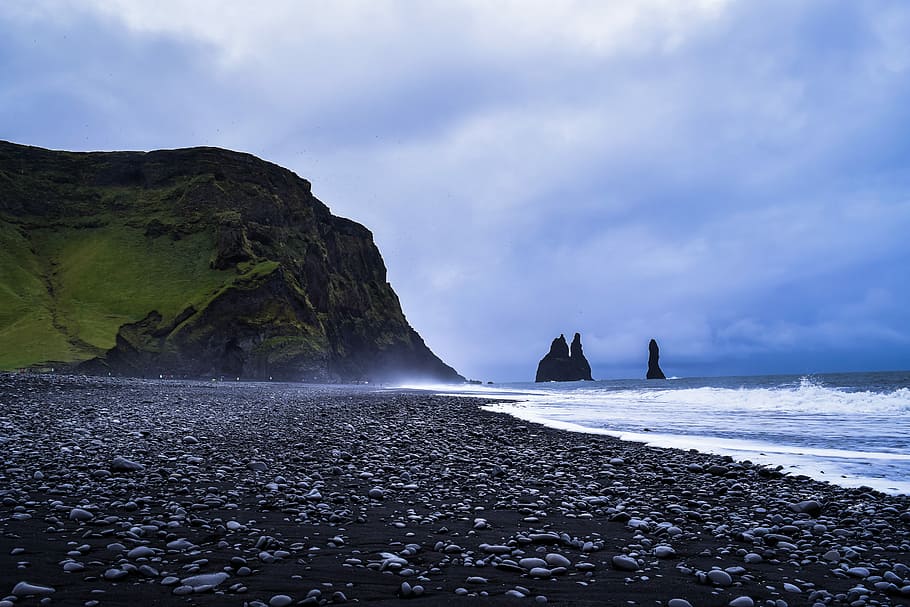 sea front of rock formation under blue and white skies, low angle photo of seashore near sea cliff during daytime HD wallpaper