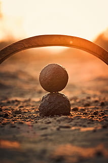 shallow focus photography of round stone mounted on black stone during sunset HD wallpaper