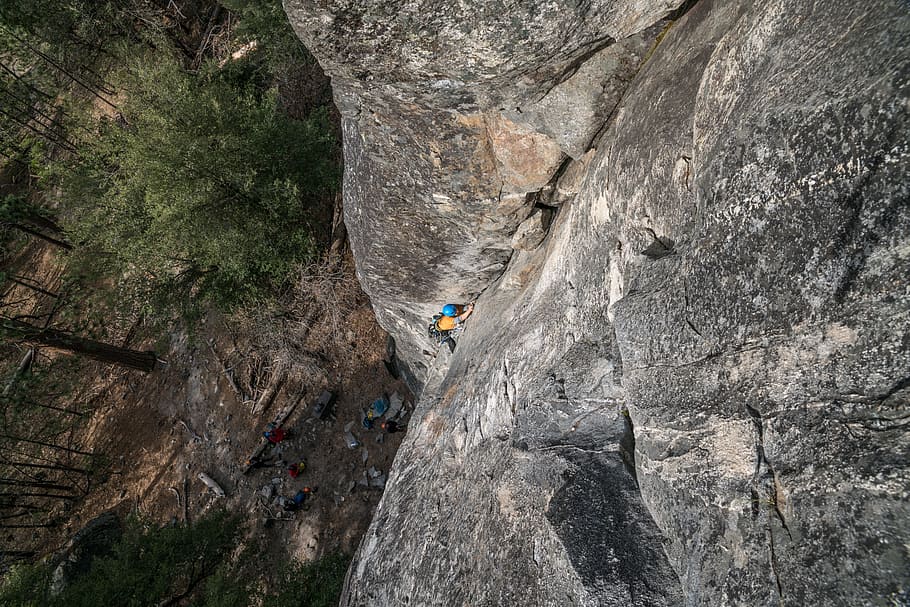 person climbing on gray rock formation at daytime, person doing mountain climbing