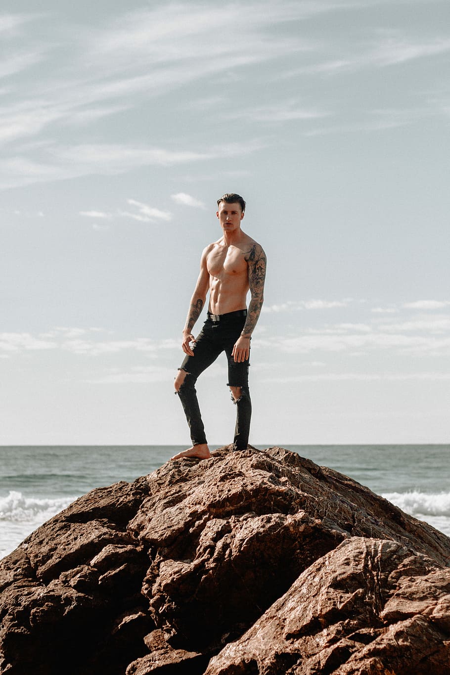 man in black pants standing on hill, man standing on rock during daytime