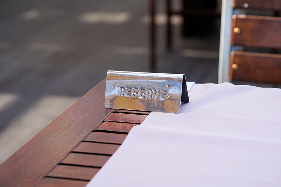selective focus photo of gray stainless steel reserve embossed ornament on brown wooden table HD wallpaper