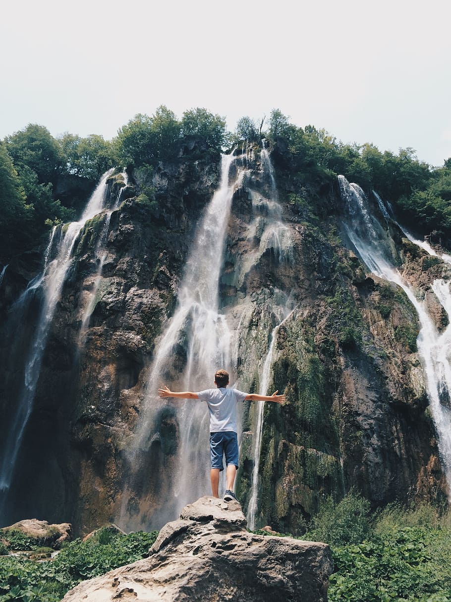 man standing on rock facing a waterfalls, hill, green, grass, HD wallpaper