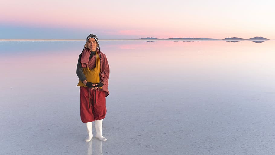 person standing on body of water during daytime, person standing on salar de uyuni during daytime