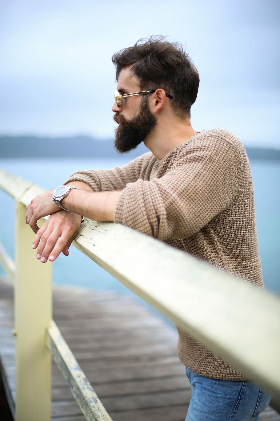 man wearing brown sweater standing on wooden dock, man wearing brown sweater lean on white metal rail during daytime, HD wallpaper