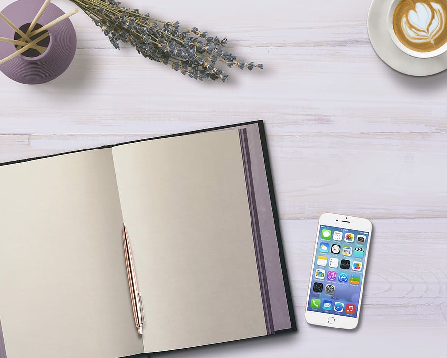 silver iPhone 6 turned-on beside book page, diary, mobile phone