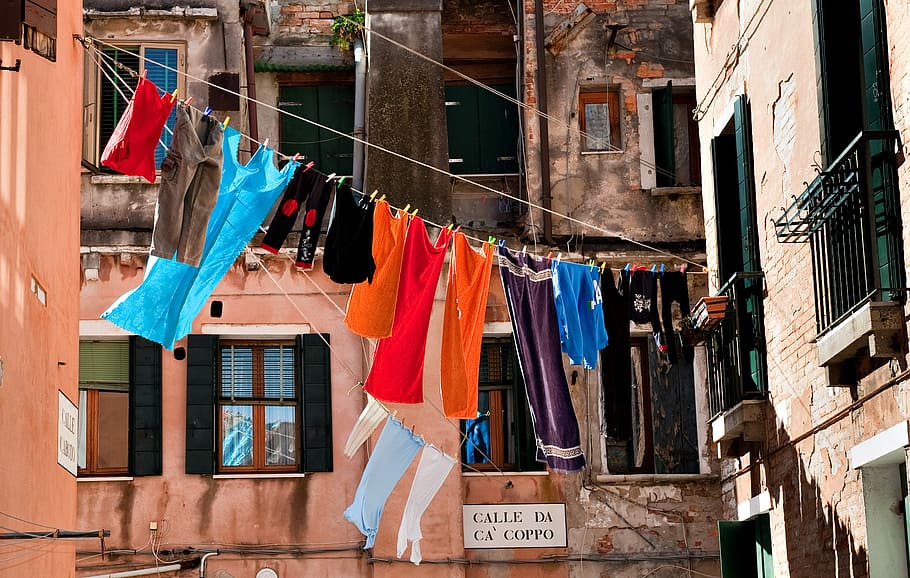 hang assorted-color clothes at daytime, clothes hanged between buildings