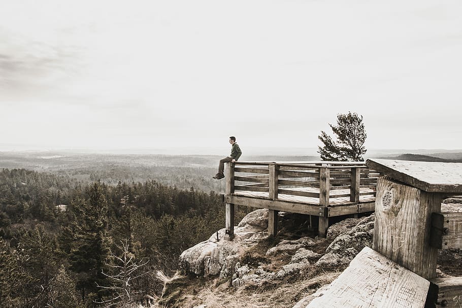 person sitting on brown wooden railings surrounded by trees, man sitting on mountain dock HD wallpaper