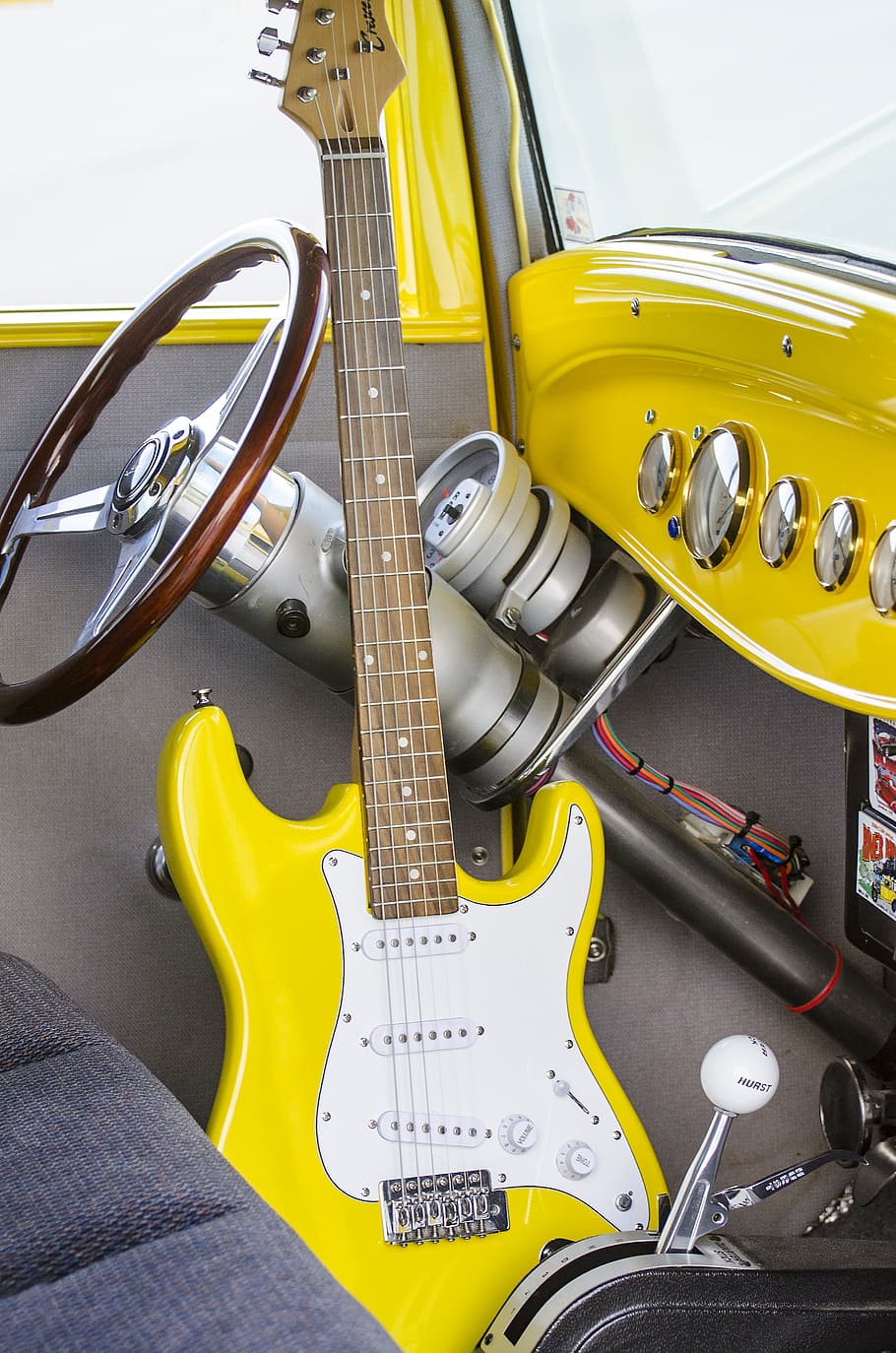yellow electric guitar in yellow and gray interior car, steering wheel