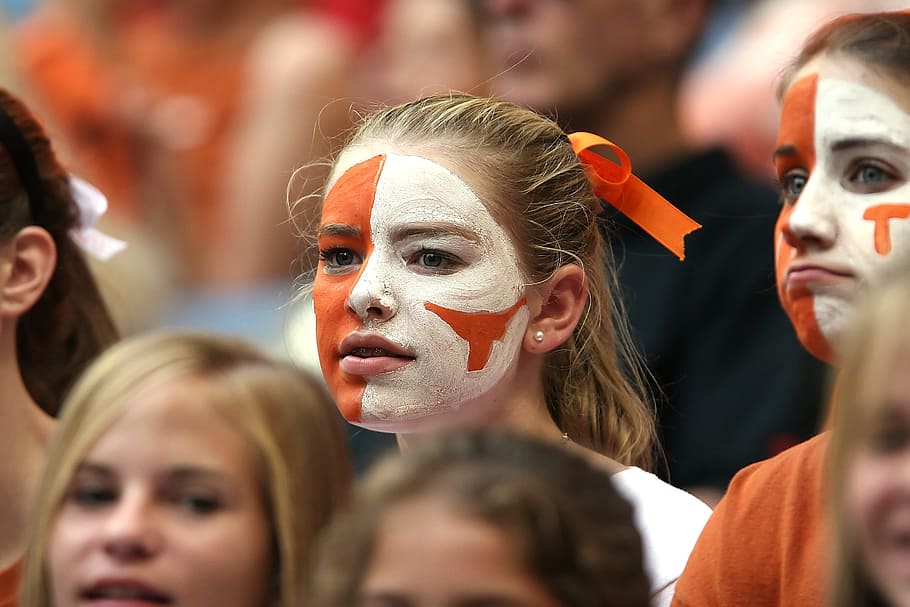closeup photo of woman with white and orange paint on face, american football