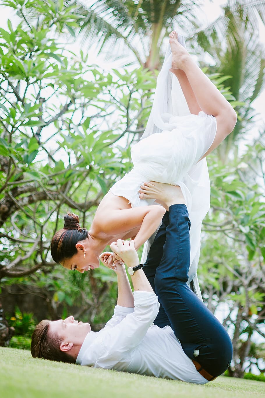 man lifting woman with both hand and feet during daytime, yoga