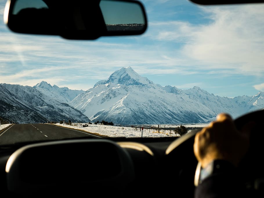 man driving towards mountain coated with snow, person driving car towards snow capped mountains at daytime HD wallpaper