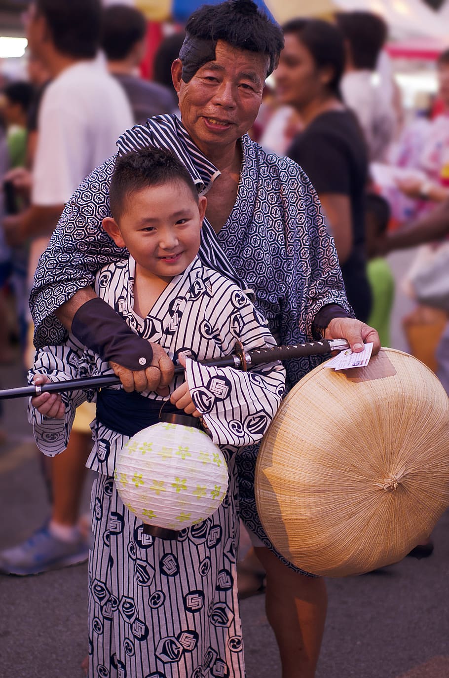 man holding hat and sword standing with boy during daytime, bon odori