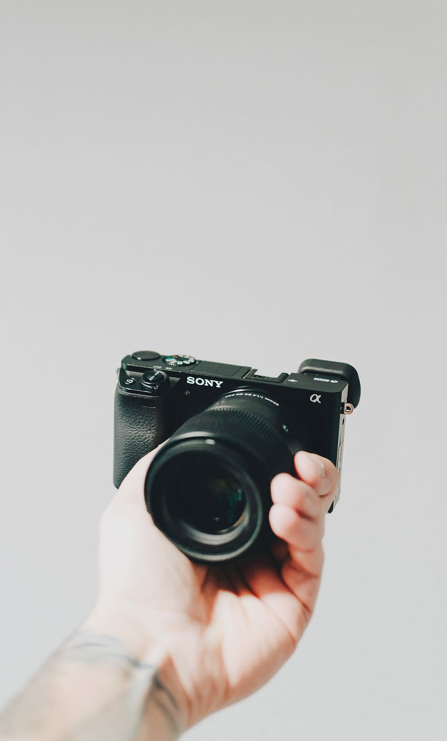 person holding black Sony Alpha camera, person hand holding Sony bridge camera HD wallpaper