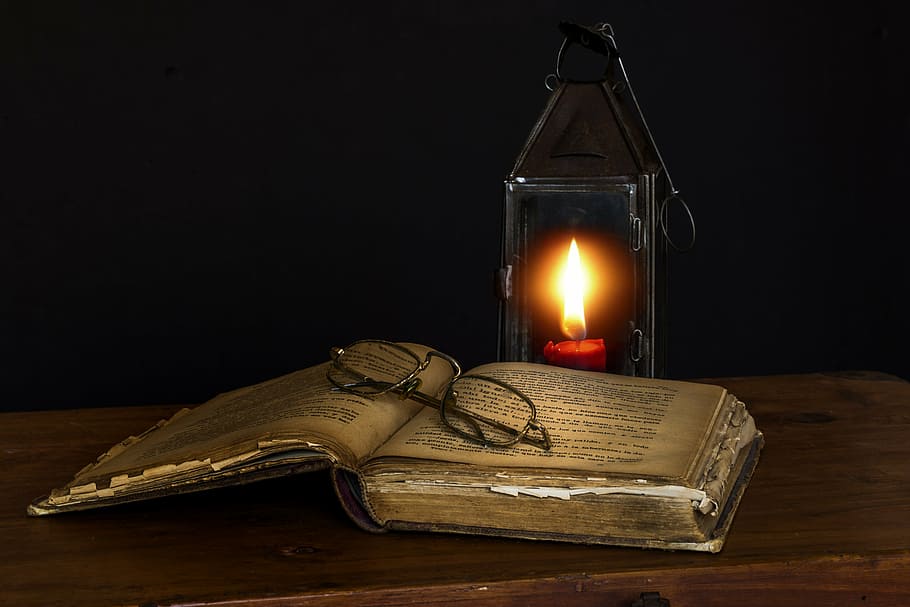 lighted candle near books and eyeglasses, old books, reading