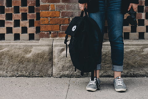 person standing near brown concrete wall, woman holding backpack HD wallpaper