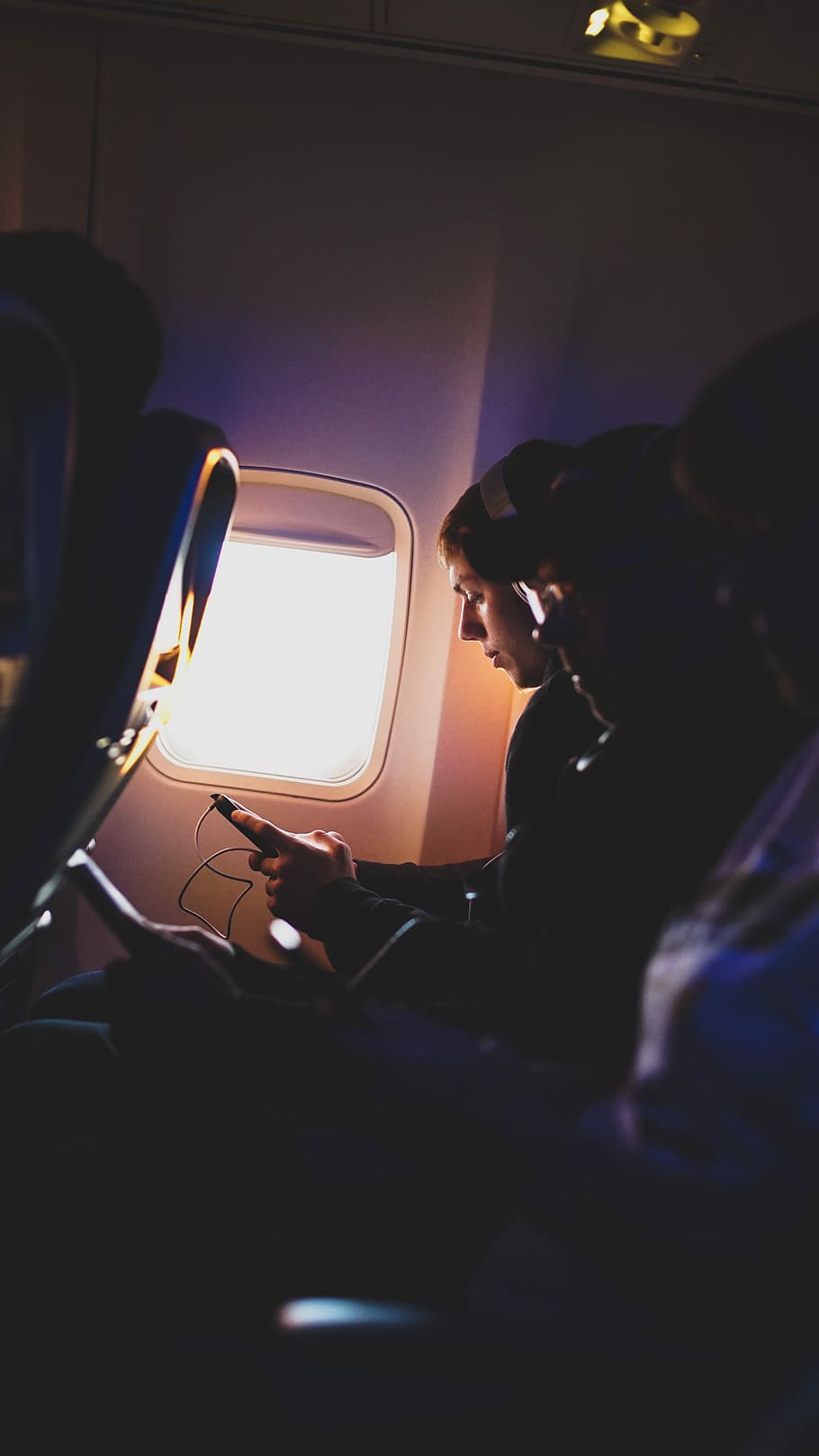 photo of three people listening to music inside airplane, selective focus photography of person riding on plane while holding smartphone, HD wallpaper
