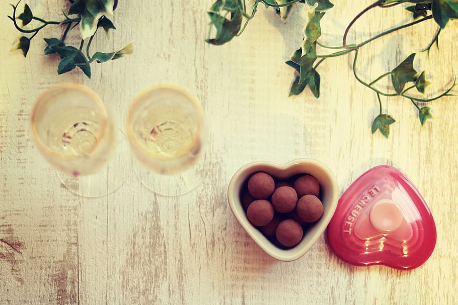 two clear long-stem wine glass beside heart-shaped ceramic container filled with pastries HD wallpaper