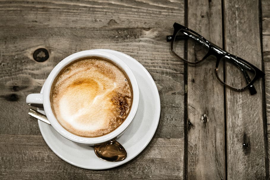 white ceramic mug filled with cappuccino, black framed Wayfarer-style eyeglasses beside white ceramic teacup filled with coffee HD wallpaper