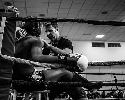 greyscale photography of a boxer inside reing, coach talking to boxer on ring's corner in grayscale photography HD wallpaper