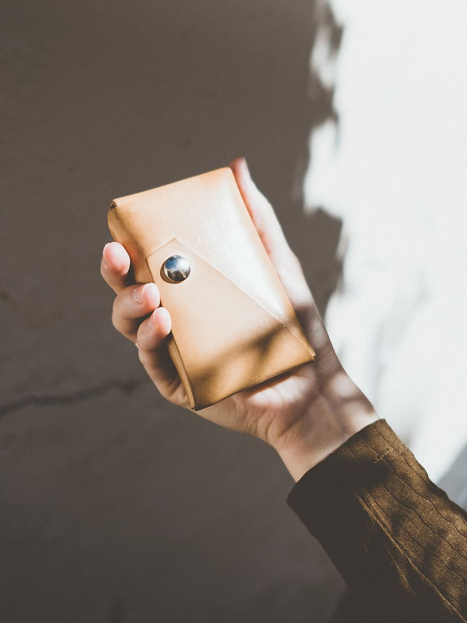person in brown long-sleeved shirt holding brown leather case, person holding brown leather wallet HD wallpaper