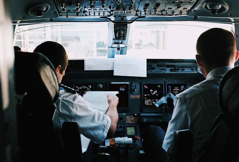 two men inside the plane, person reading document, pilot, cockpit