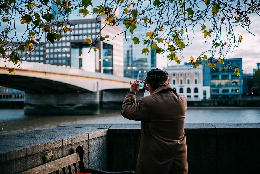 man standing beside river near concrete bridge, person taking photo of road outside HD wallpaper