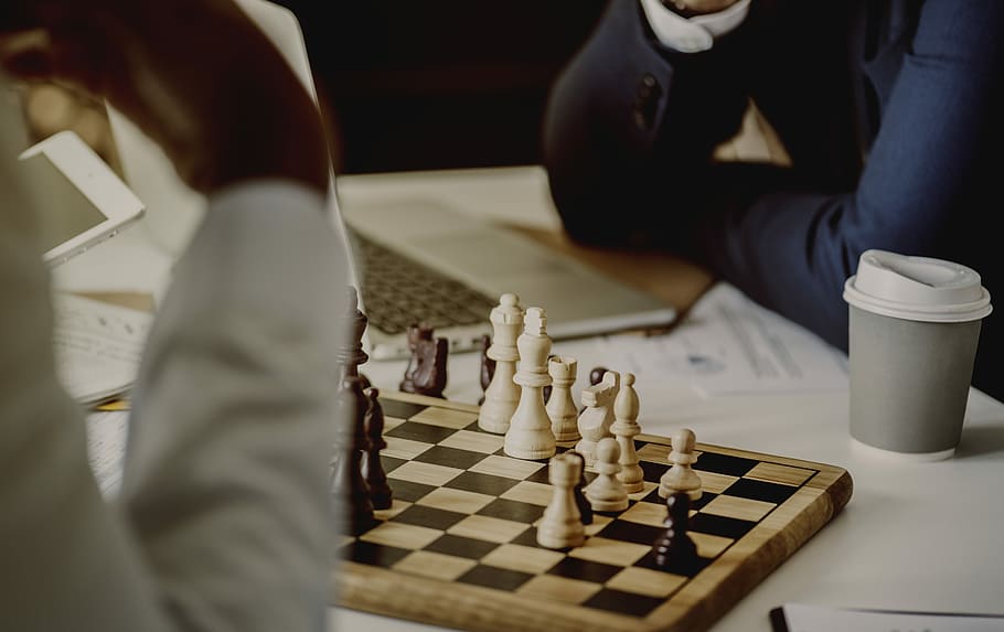 people wearing white and black long-sleeved shirts playing chess