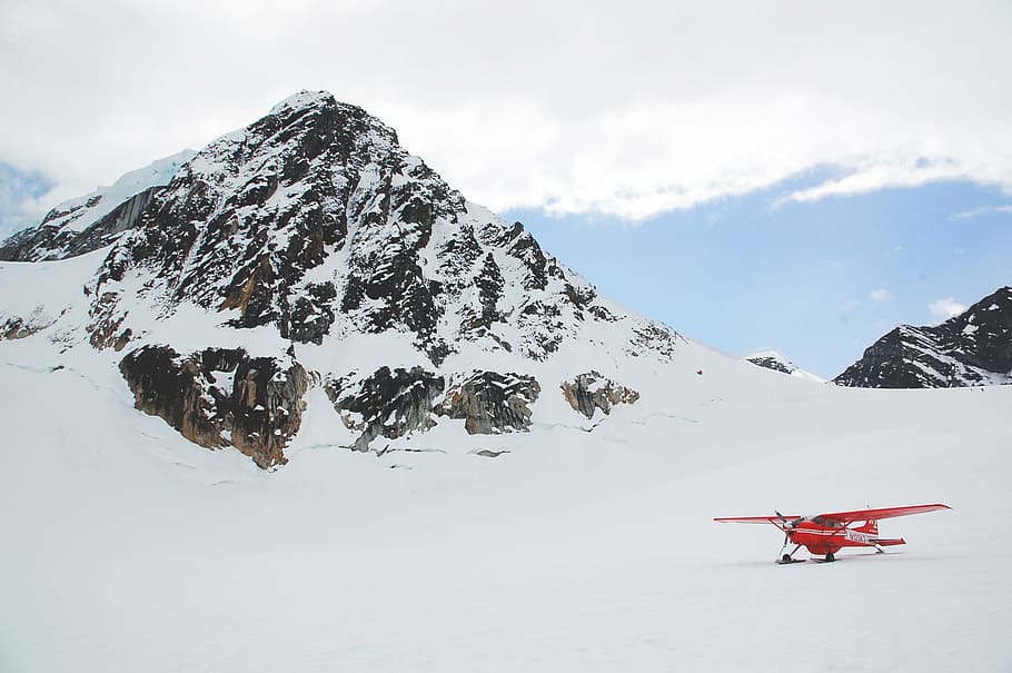 red stunt plane on snowy mountain, monoplane, daytime, mountains HD wallpaper