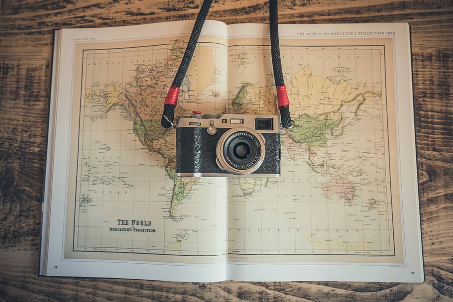 black and gray camera on open map, black and silver camera on top of world map
