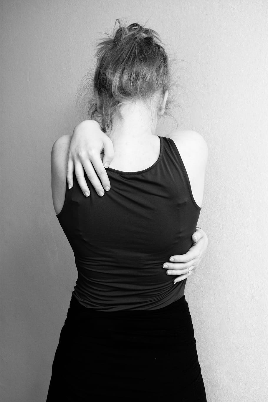 woman in black tank top hands on her back, hug, desperate, sad