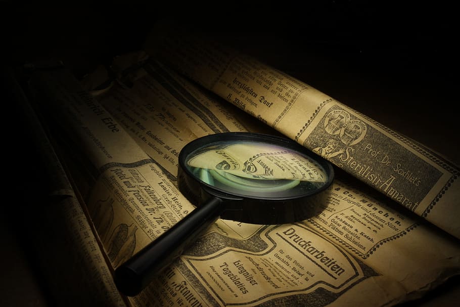 photography of magnifying glass on printed brown paper, black