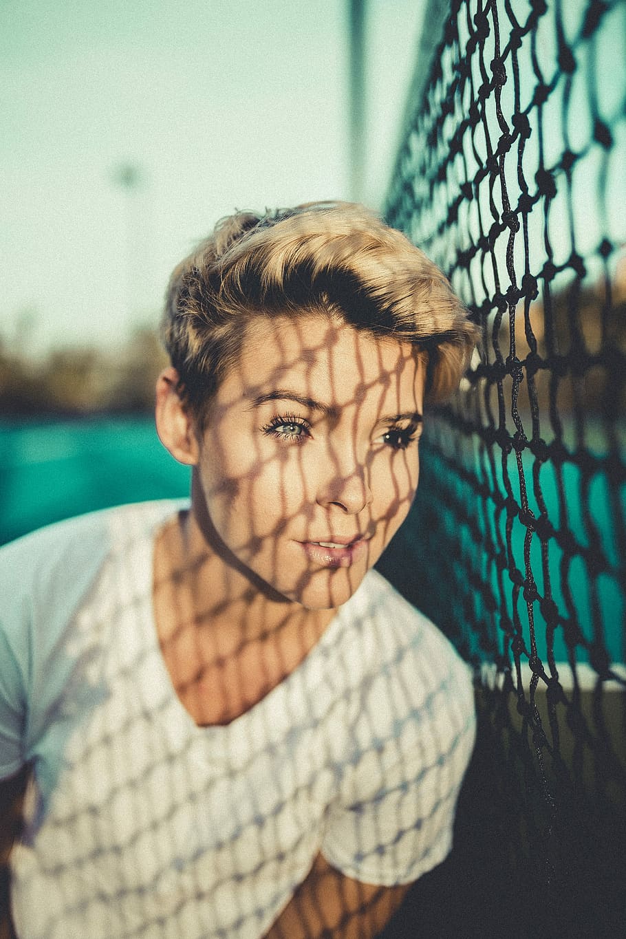 close up photo of woman with V-neck t-shirt close to black net, shallow focus photography of girl standing beside net HD wallpaper