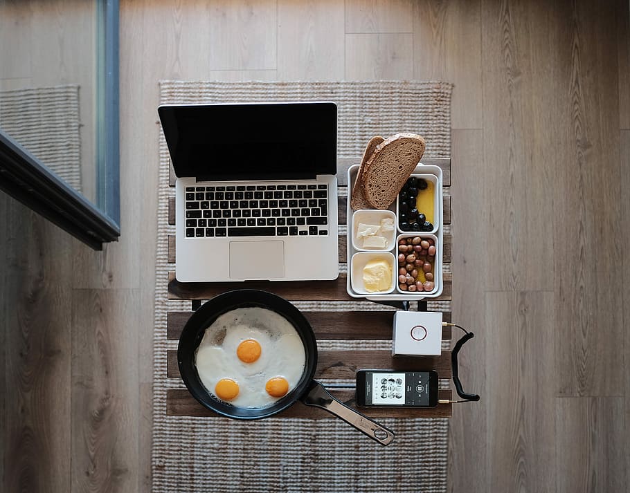 photo of MacBook Pro, frying pan with eggs and bread on gray mat, flat lay photography of MacBook and food HD wallpaper