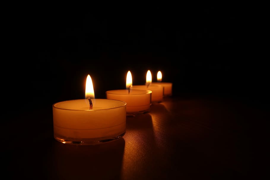 close up photo of four lighted tealight candles, tea lights, candlelight