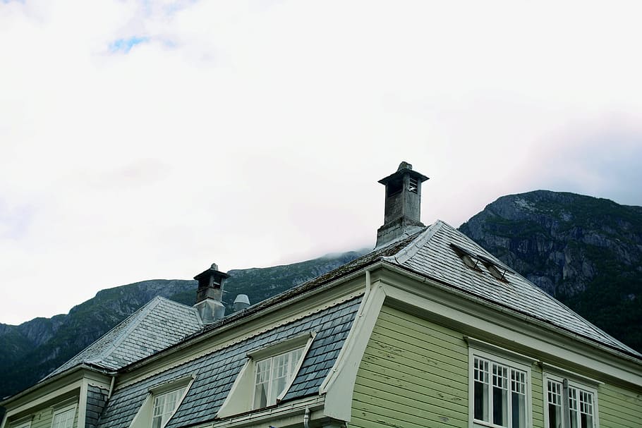 photo of brown and yellow house near rocky mountain under cloudy sky, white concrete windowpane HD wallpaper