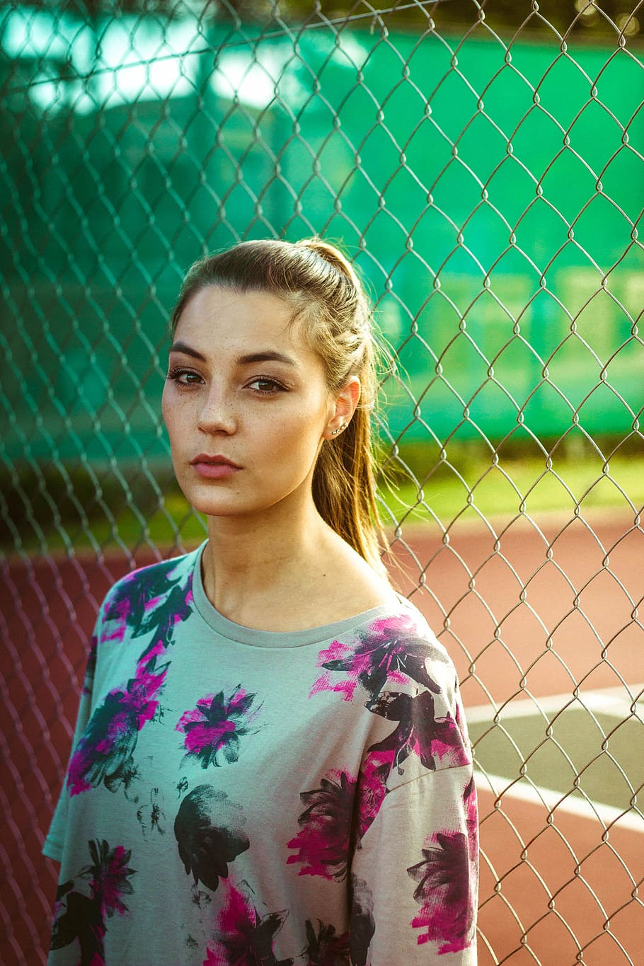 woman wearing floral top beside chain link fence during day, woman wearing multicolored floral shirt standing beside gray metal fence during daytime, HD wallpaper