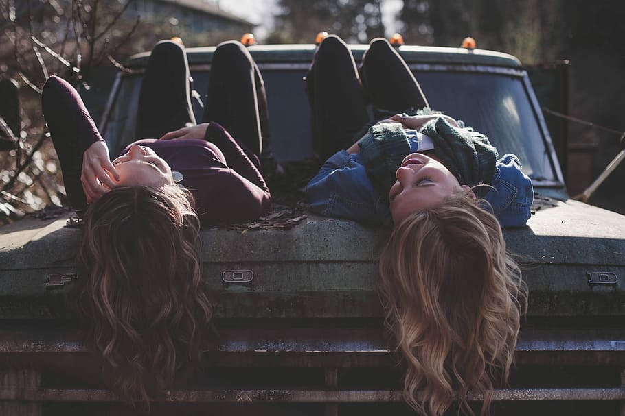 two women lying down on vehicle, two woman lying on vehicle at daytime, HD wallpaper
