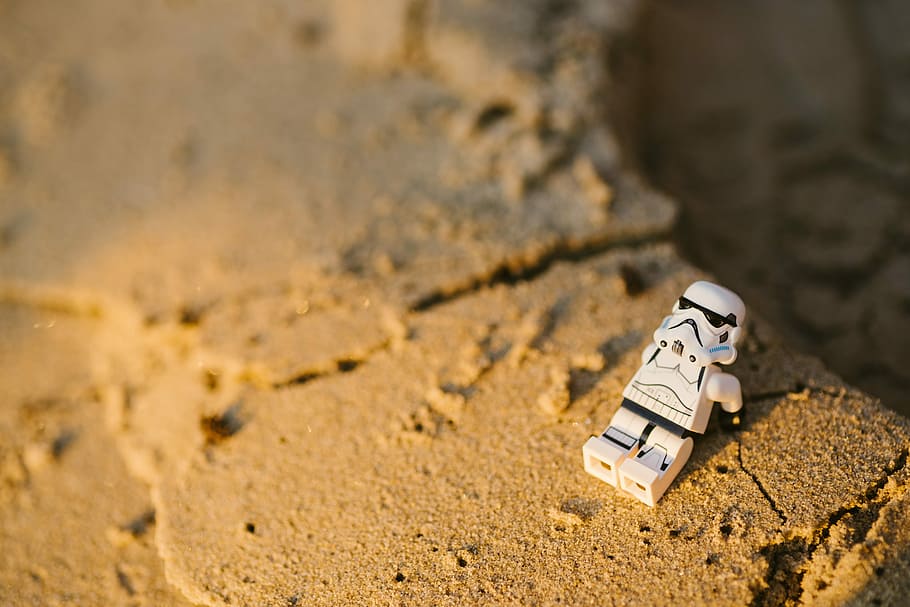 selective focus photography of Star Wars Stormtropper minifigure on sand, Storm Troopers mini figure on brown sand HD wallpaper