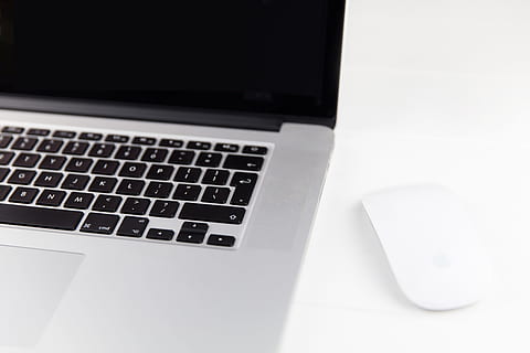 Apple Macbook Pro laptop computer and Magic Mouse situated on a minimalist pure white wood desk HD wallpaper