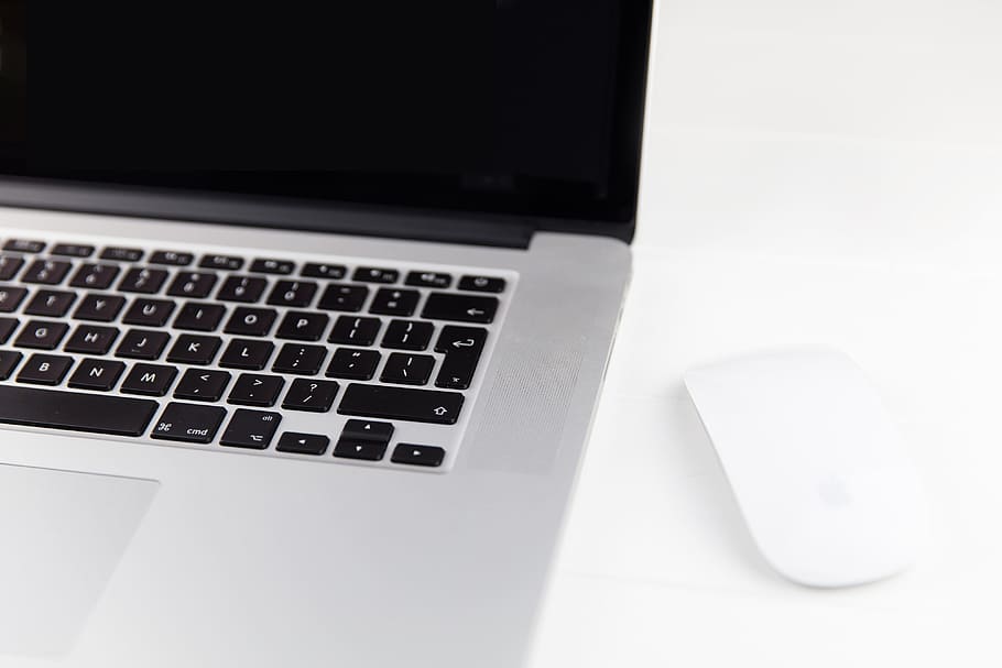Apple Macbook Pro laptop computer and Magic Mouse situated on a minimalist pure white wood desk HD wallpaper