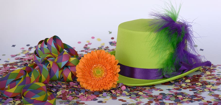 green and purple hat beside orange flower on top of confetti HD wallpaper