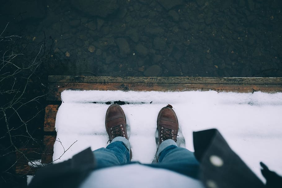 person standing on the edge of brown wooden surface, man in blue jeans and white top wearing brown shoes standing on snow HD wallpaper