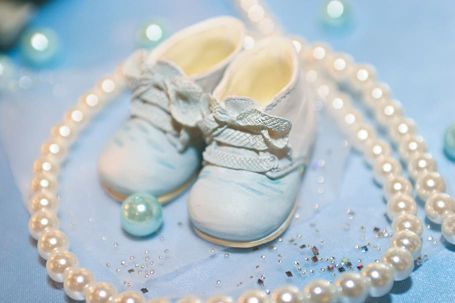 baby's white shoes surrounded by white pearls, baby shoes, cyan light blue
