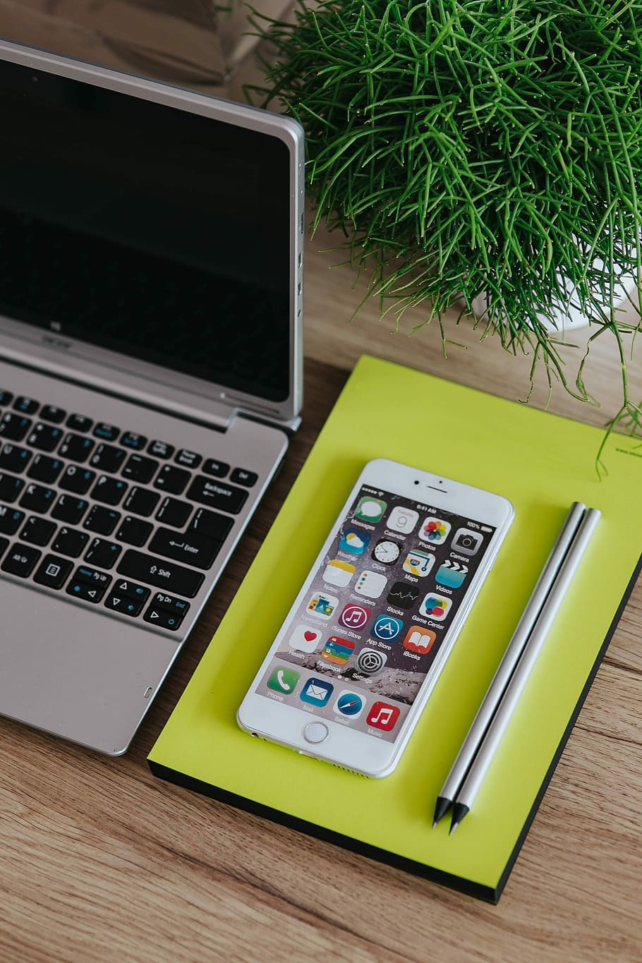 Silver Acer laptop, a white Apple iPhone and a notepad on a wooden desk HD wallpaper
